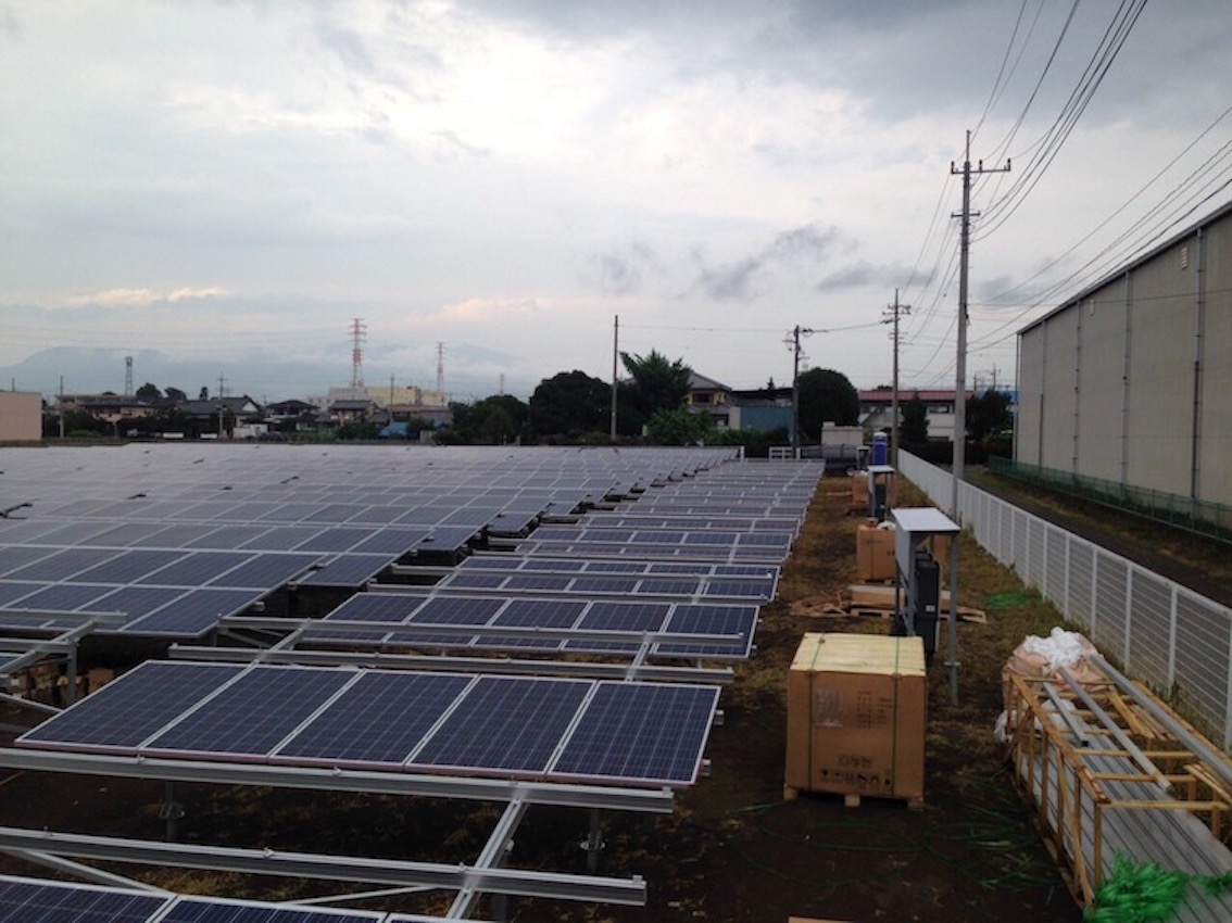 大規模太陽光発電所の施工中の様子。架台組み立てとパネル部材のパレットが並ぶ現場