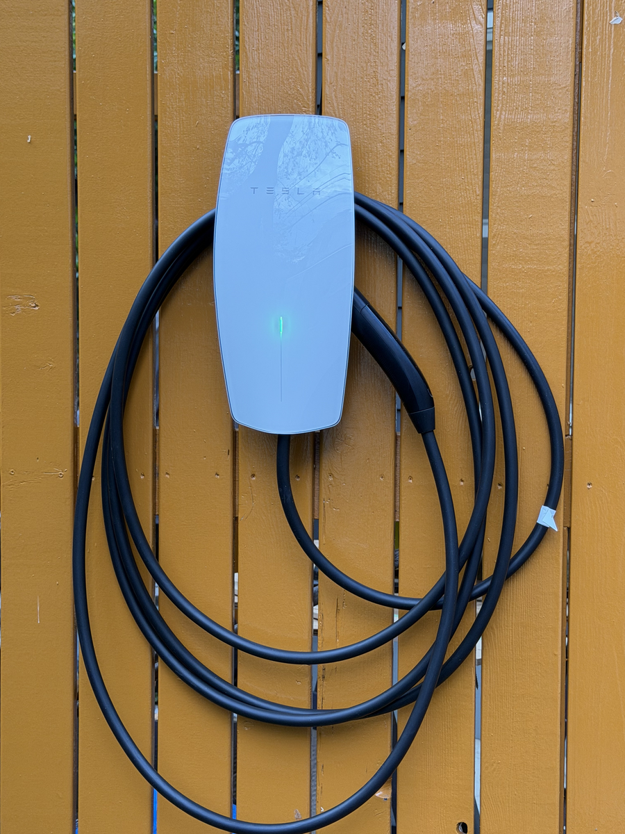 木目調の壁面に設置した白色のTesla Wall Connector