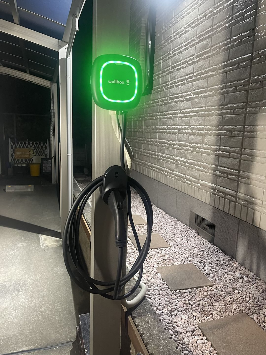 夜間に動作中のWallbox充電器（緑LED点灯）の壁面設置例
